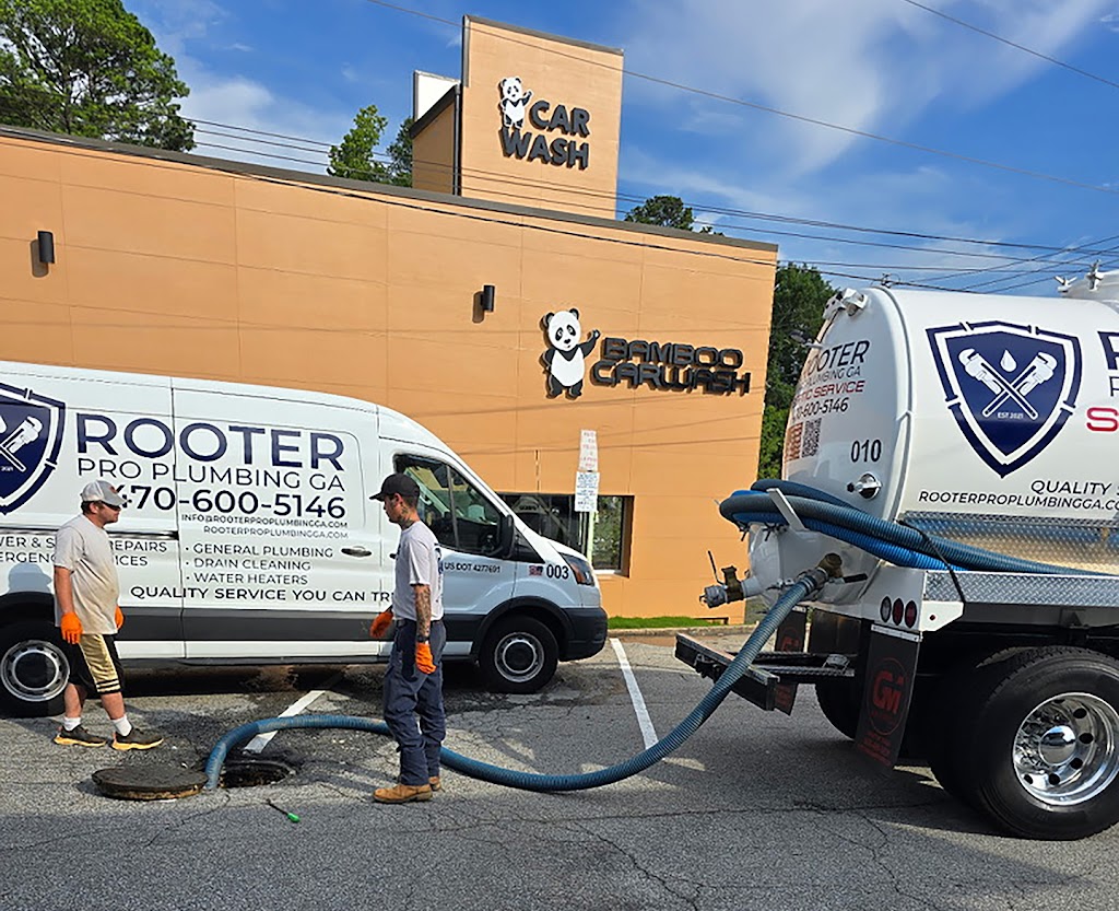 Rooter Pro technicians performing commercial sewer service at Bamboo Car Wash with branded vans